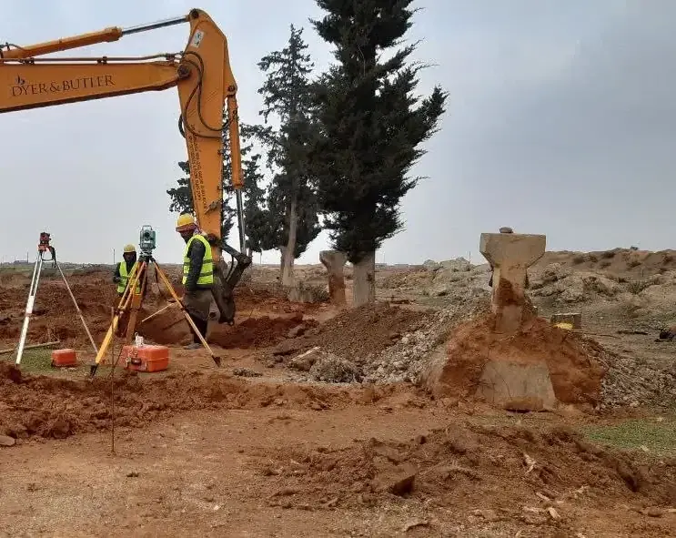 فريق المساحة بالسترات والخوذ عند الحفر